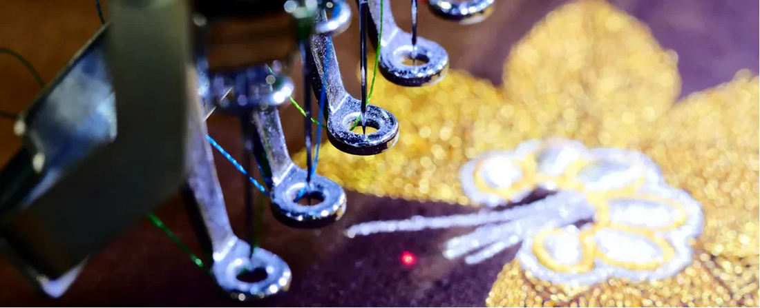 Machine à broder réalisant une broderie dorée personnalisée sur tissu de façon artisanale