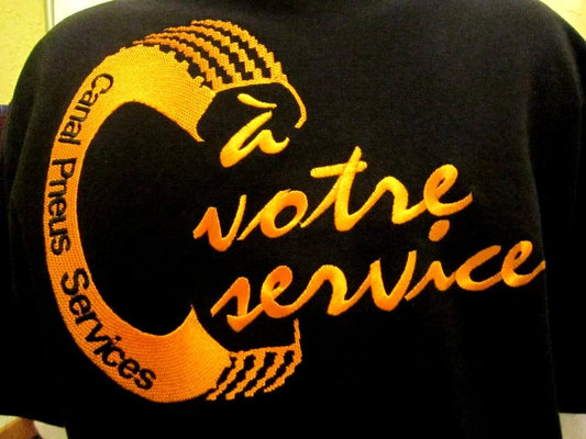 Logo brodé orange Canal Pneus Services sur textile noir, slogan à votre service visible.