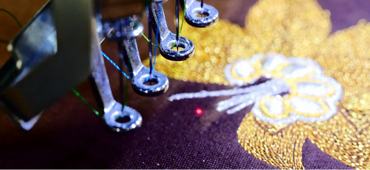 Machine à broder réalisant une broderie dorée florale sur tissu, gros plan artisanal