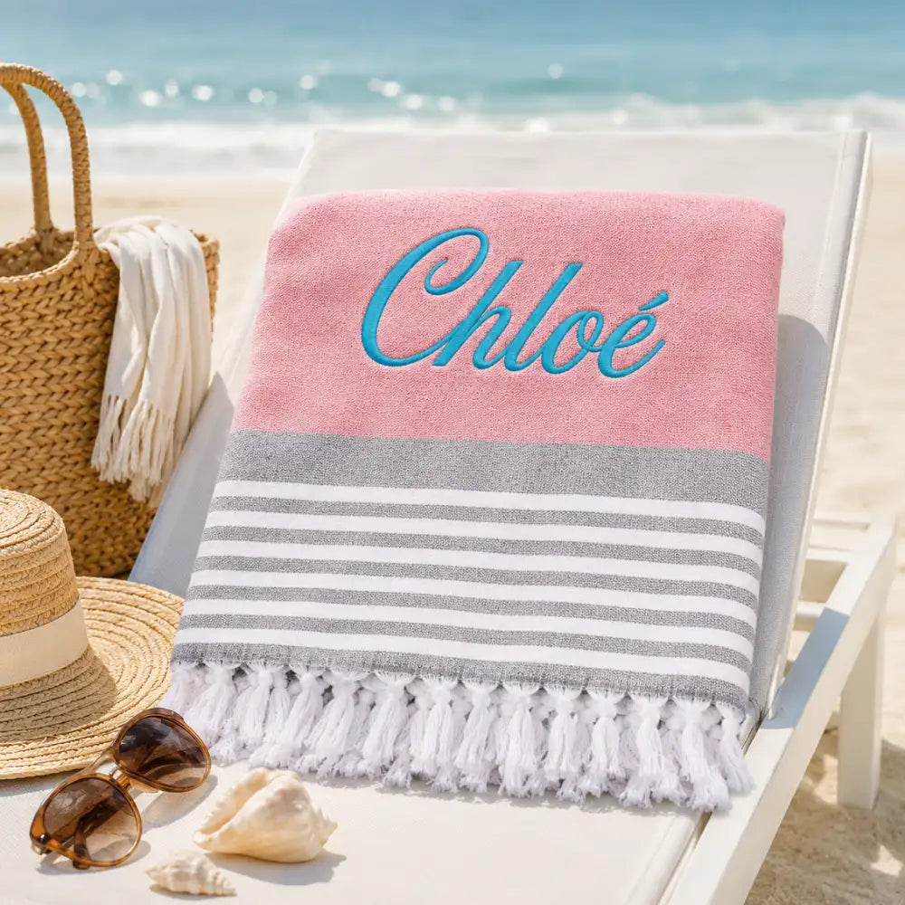 Fouta personnalisée rose brodée au prénom Chloé en fil turquoise, serviette plage coton turc à franges sur transat