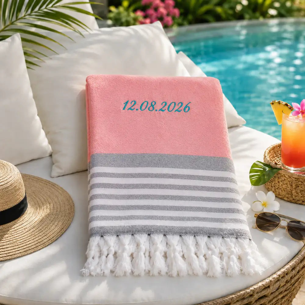 Fouta personnalisée rose brodée d'une date 12.08.2026 en fil turquoise, serviette coton turc à franges au bord de la piscine
