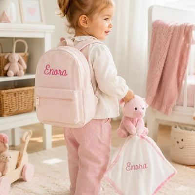 Enfant de dos avec sac à dos rose personnalisé Enora et doudou ourson brodé dans sa chambre